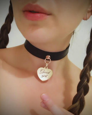 Black choker with a rose gold love heart 'Good girl' heart pendant on a neutral background